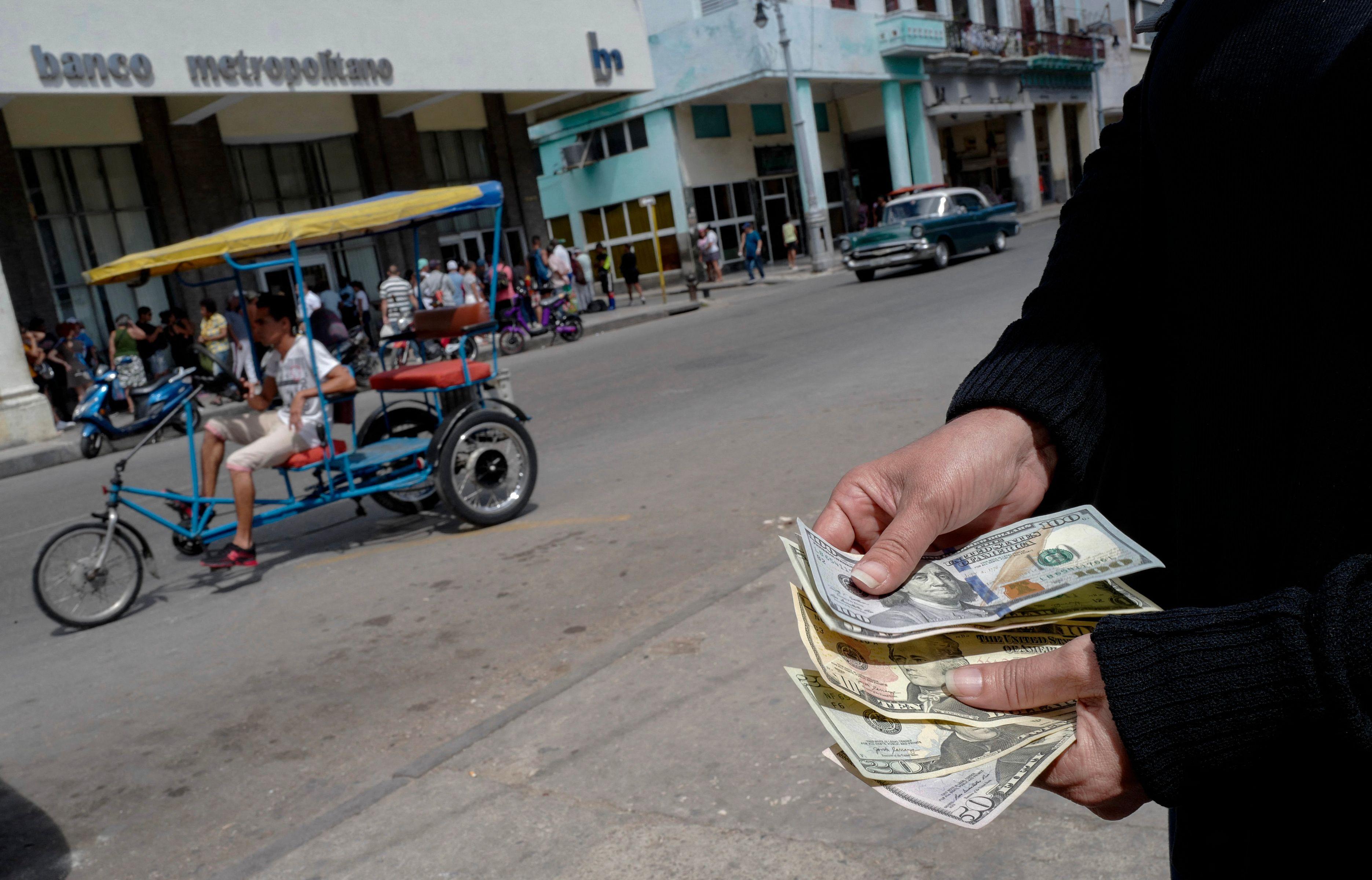 Una persona cuenta dólares estadounidenses en el exterior de un banco en La Habana, Cuba. Foto: Adalberto Roque/AFP/Archivo. 