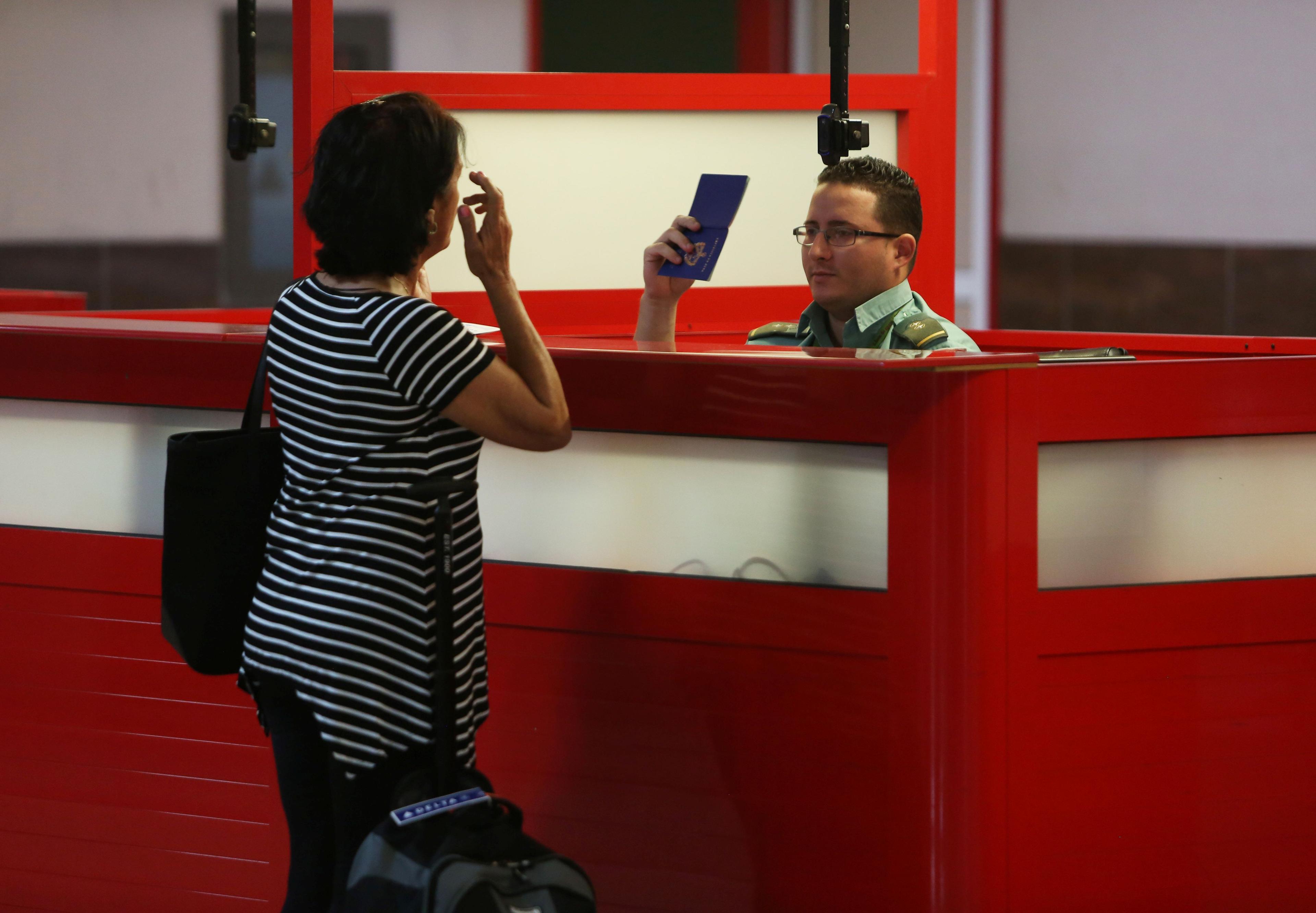 Un oficial de aduanas revisa el pasaporte cubano de una viajera. (REUTERS/Stringer)