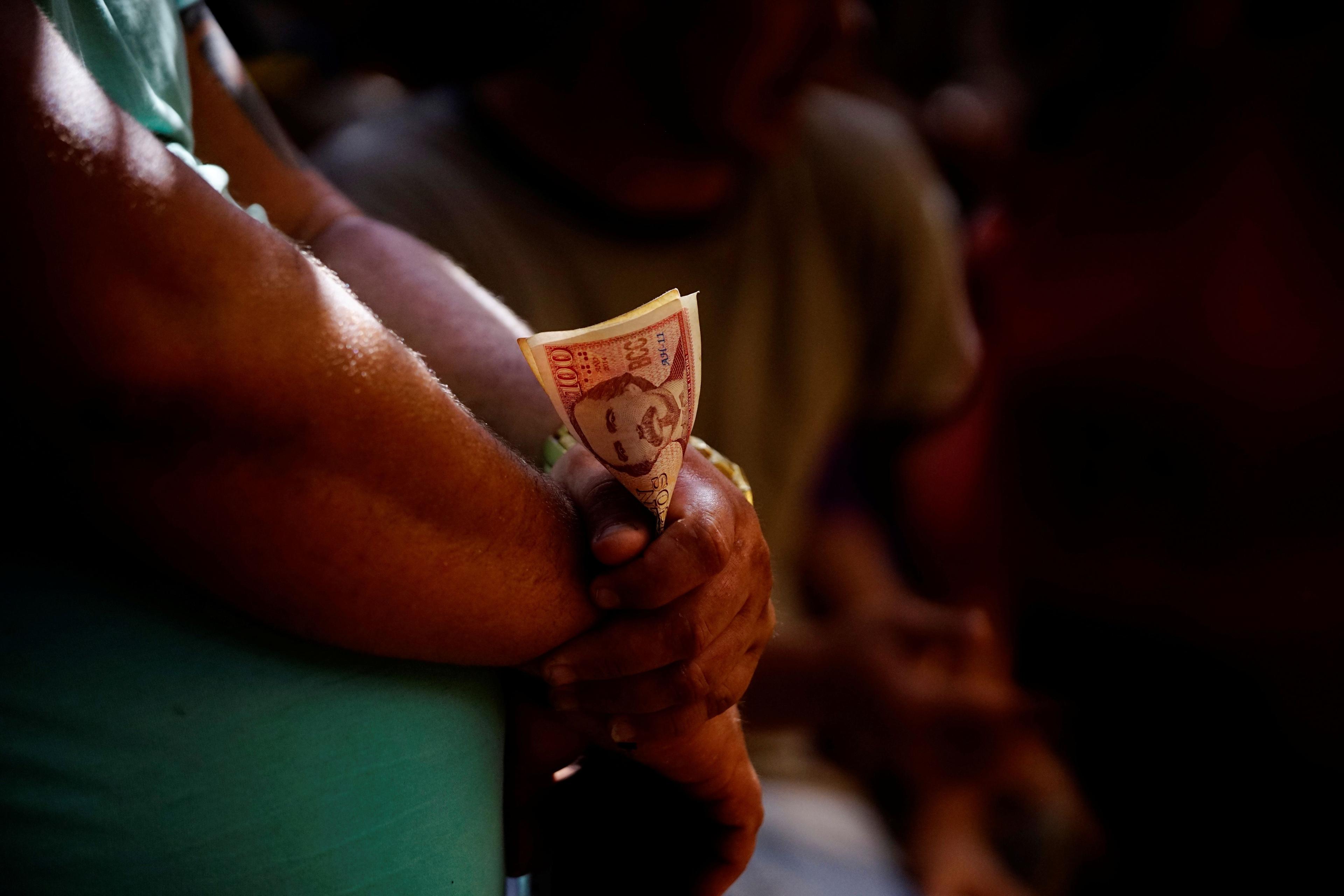 Un hombre sostiene dinero (pesos cubanos). Foto: REUTERS/Alexandre Meneghini/Archivo.