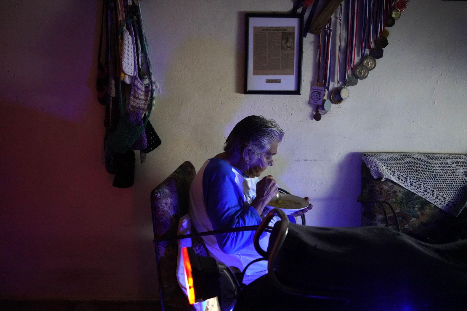 Una mujer come en su casa junto a una motocicleta que le proporciona electricidad durante un apagón en Matanzas, Cuba, el 18 de octubre de 2024. Foto: Antonio Levi/AFP. 