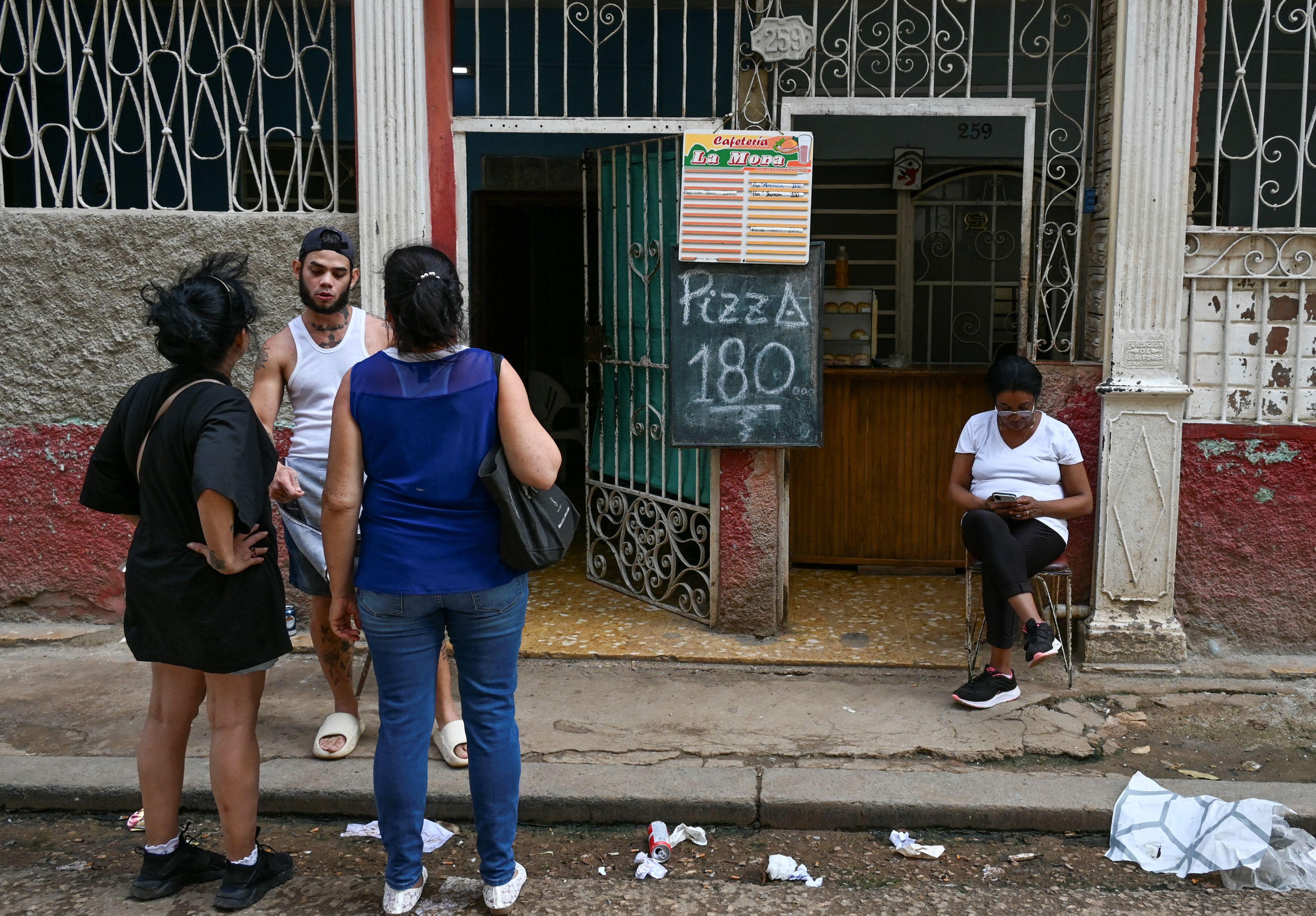 Personas frente a un negocio privado de venta de pizzas en La Habana el 22 de octubre de 2024. Foto: Yamil Lage/AFP. 