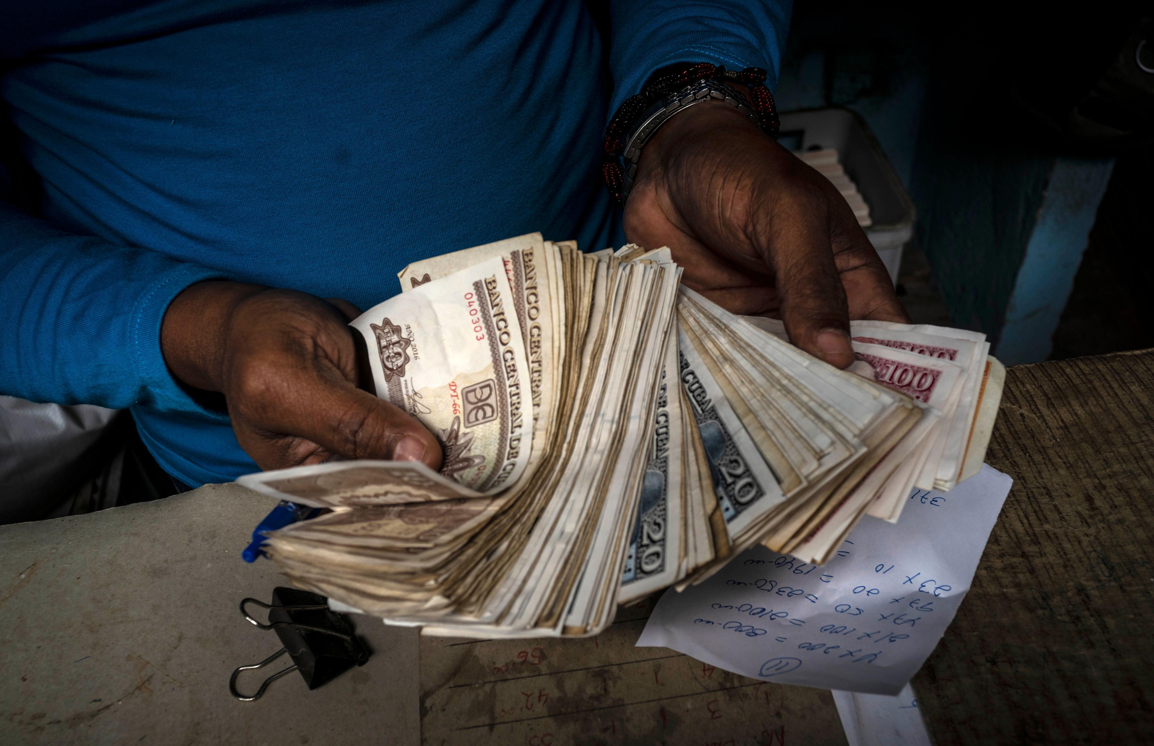 Un cubano sostiene un fajo de billetes. Foto: Ramón Espinosa/AP.