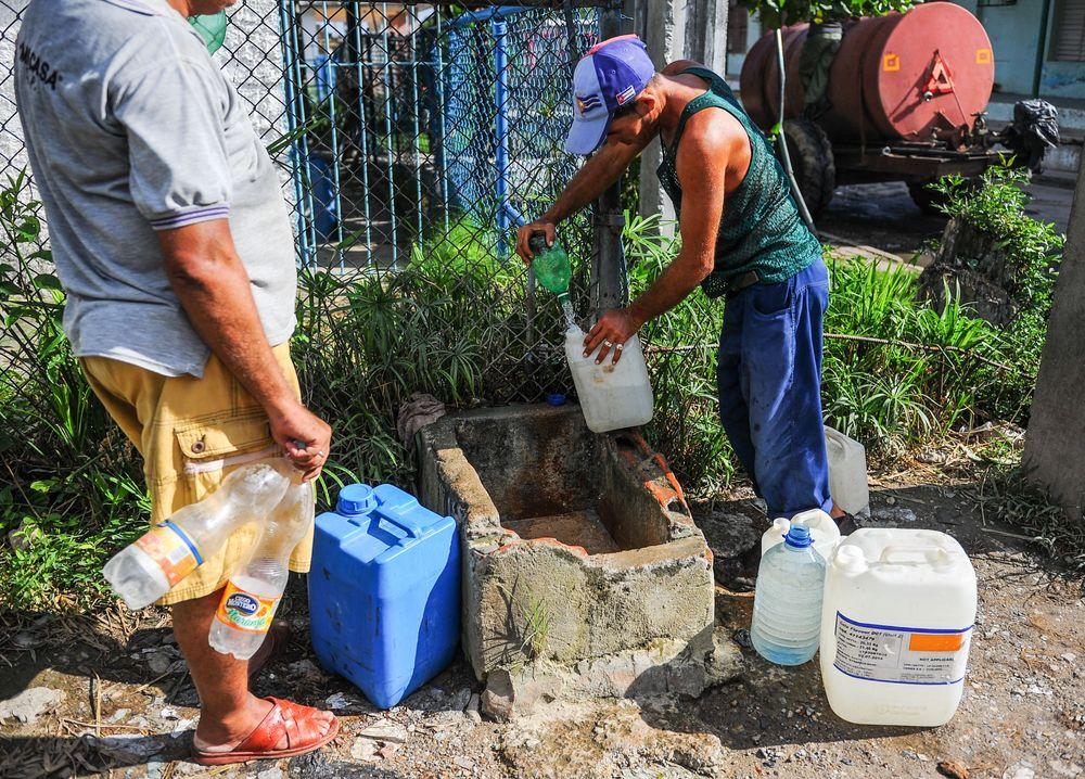 Un hombre llena botellas con agua en el barrio Consolación del Sur en la provincia de Pinar del Río, Cuba. Foto: Yamil Lage / AFP /Archivo. 