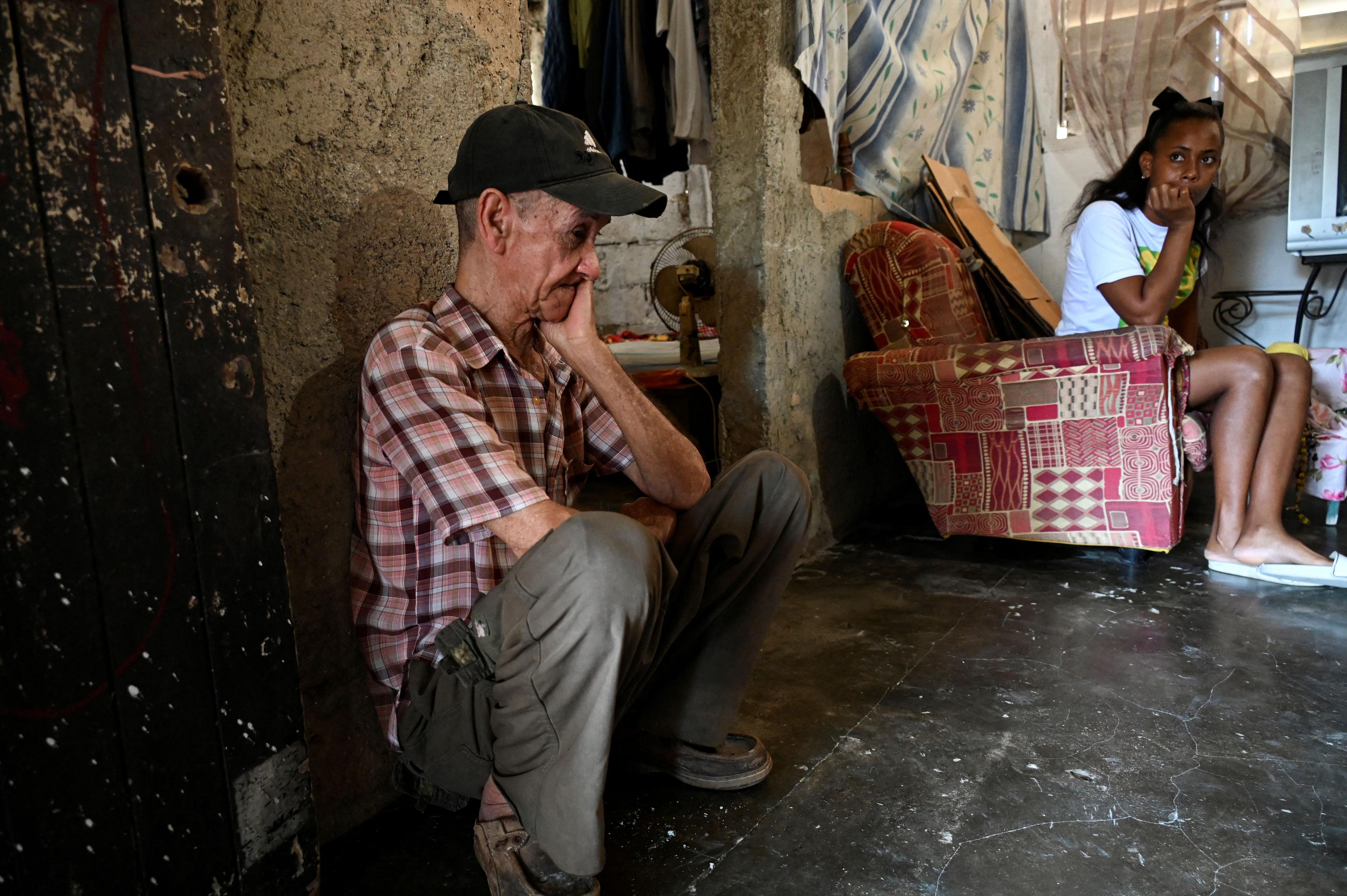 Lázaro Ruiz se sienta en el suelo junto a su hija Diana Ruiz en su casa de La Habana el 27 de marzo de 2024. Foto: Yamil Lage/AFP.