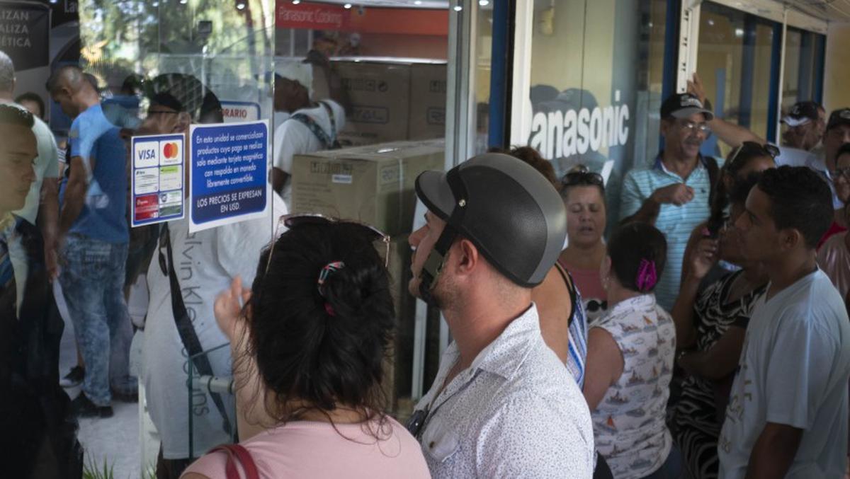  Compradores leen un cartel sobre las formas de pago en una tienda en La Habana, Cuba, Foto: AP/ Ramón Espinosa/Imagen de referencia. 