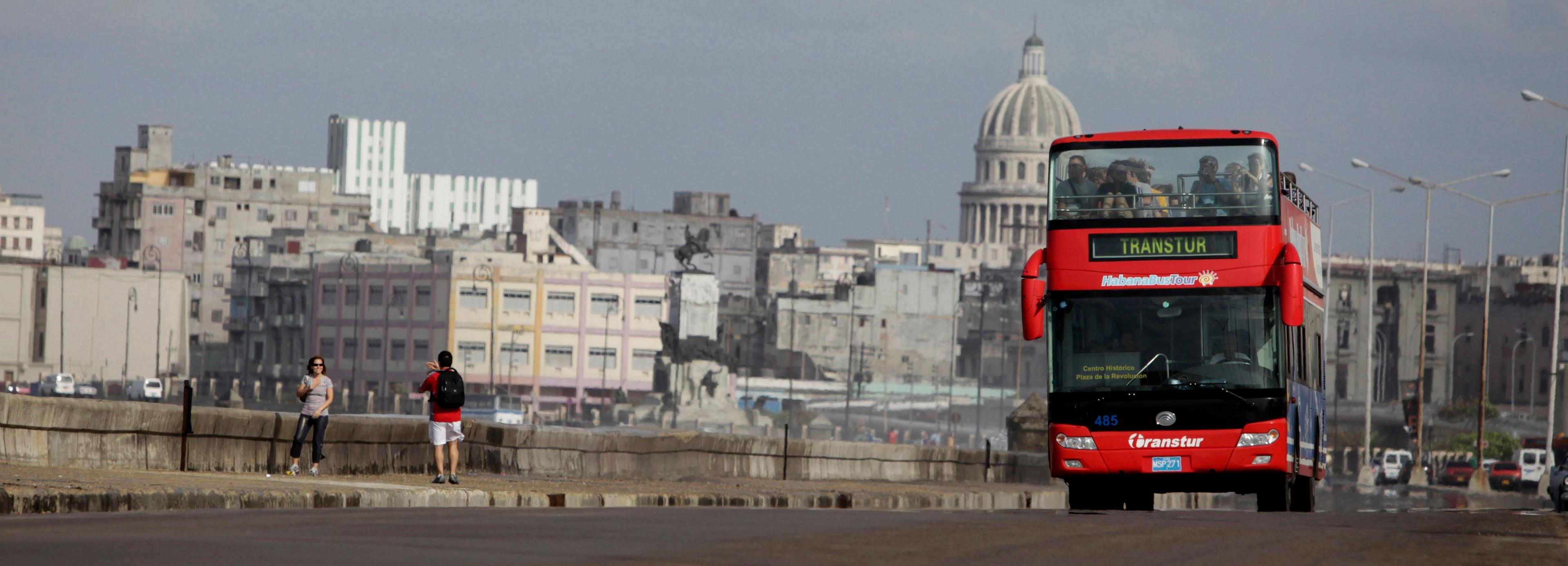 Extranjeros toman fotografías mientras un autobús turístico pasa por el Malecón de La Habana, Cuba. AP Photo/Javier Galeano/Archivo. 