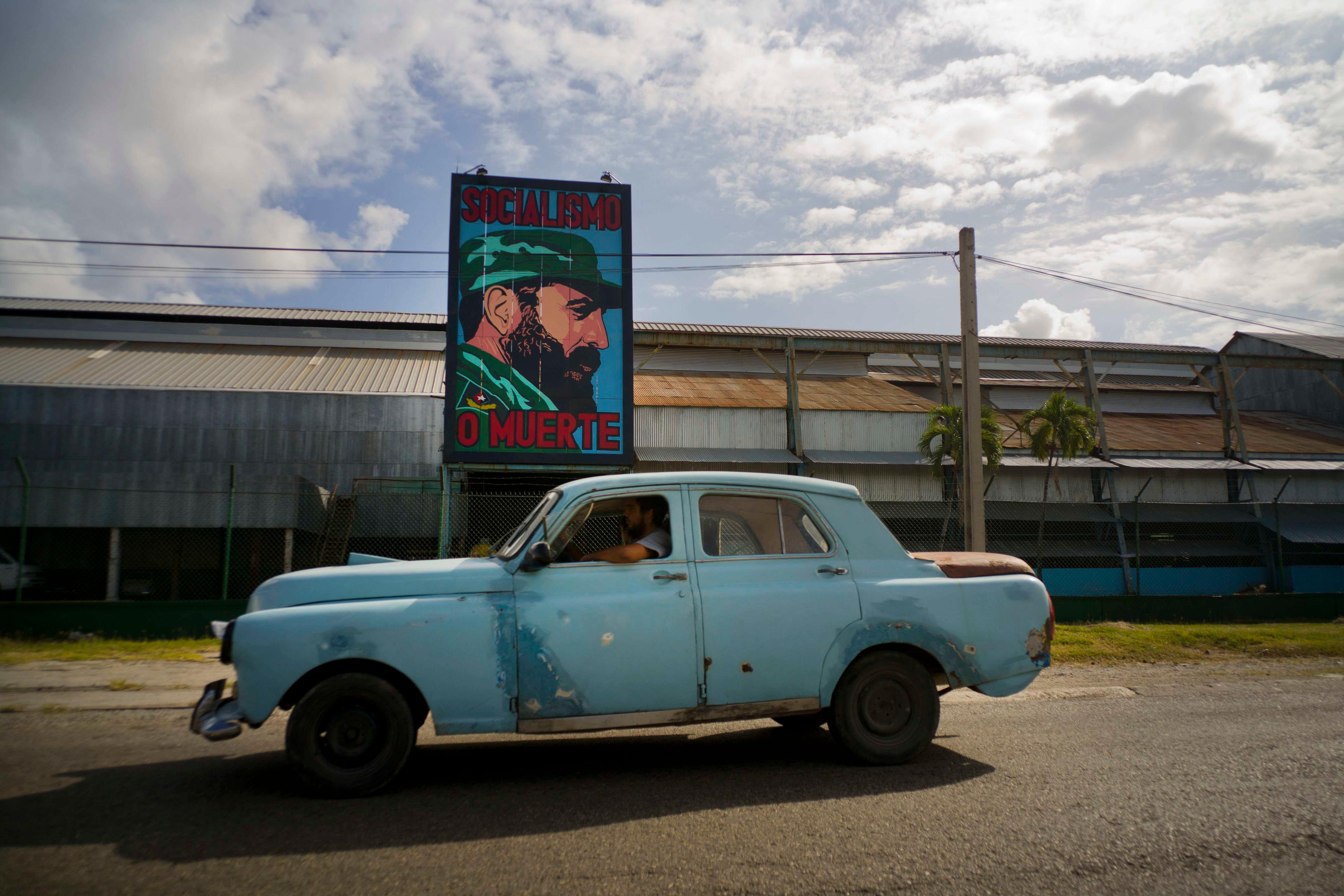  Un automóvil pasa por una fábrica con una imagen de Fidel Castro que dice Socialismo o muerte, en La Habana. (Foto AP/Ramón Espinosa) Archivo. 