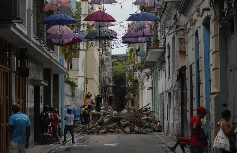  Personas observan a los bomberos retirar escombros de un edificio colapsado en la calle Lamparilla (La Habana), que dejó tres personas muertas. (AP /Ramón Espinosa/Archivo)