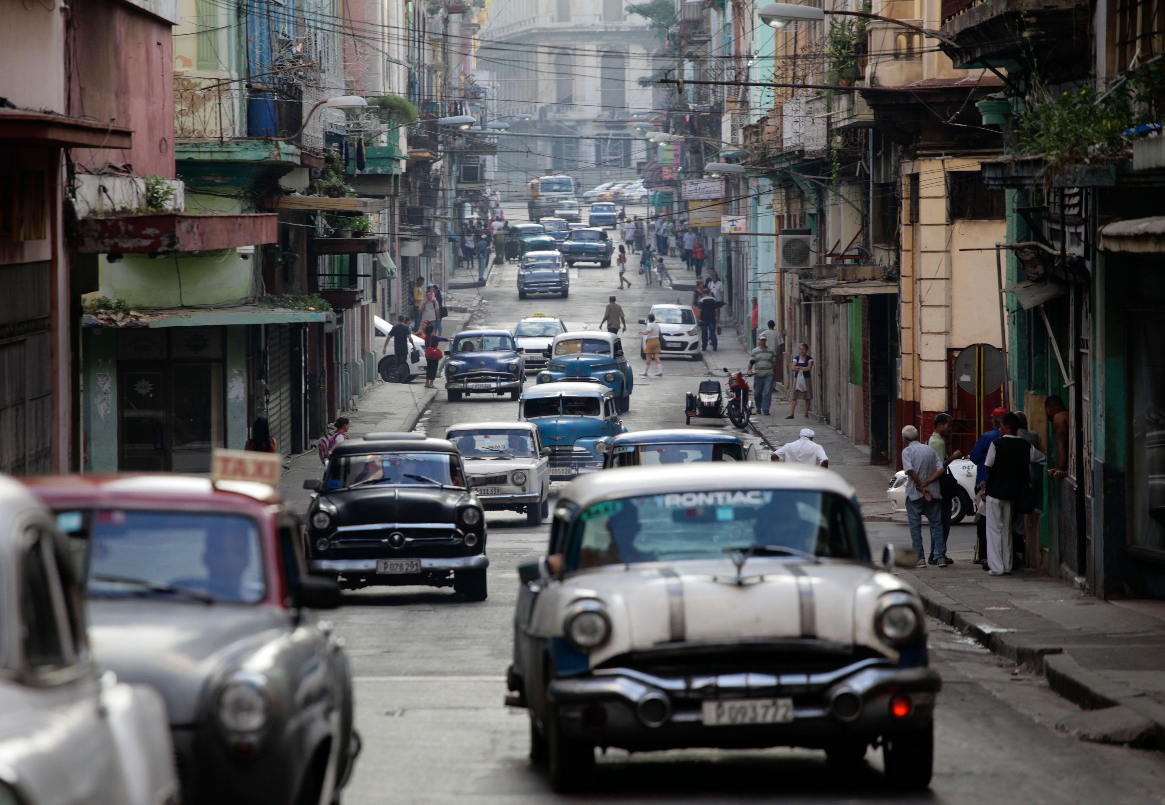 Autos clásicos americanos utilizados como taxis colectivos circulan por una calle de La Habana. (Foto AP/Desmond Boylan/Archivo)