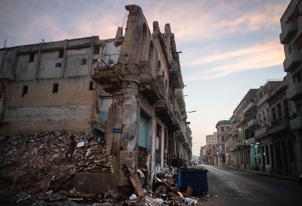 Edificios ruinosos y derrumbados bordean la calle San Lázaro, donde un hombre, a la izquierda, recoge ladrillos en el centro de La Habana (10 de octubre de 2023). (AP/Ramón Espinosa).
